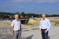 Vor der 2020 fertiggestellten Brücke an der B85 bei Ayrhof informierte Bauamtsdirektor Robert Wufka (l.) MdB Alois Rainer über den weiteren Fortgang der Arbeiten zum Ausbau der Bundes-straße: Nächste Woche geht es mit den Arbeiten für den Bau des dritten Fahrstreifens los.