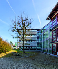 Blick vom Haupteingang an der Karlsbader Straße über den Verbindungsbau zum östlichen Bürotrakt mit neuer Wärme- und Sonnenschutzverglasung.