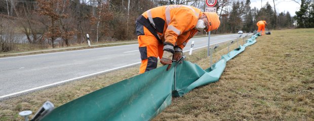 Oberhalb der Staatsstraße 2319 bei Kellberg haben die Mitarbeiter der Straßenmeisterei Hauzenberg Amphibienschutzzäune errichtet. Matthias Plankl zieht die Schutzplane straff, entlang der die Kröten zu den im Boden vergrabenen Eimern geleitet werden.