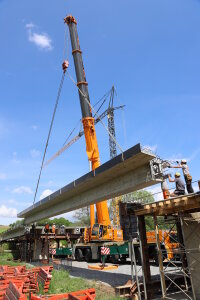 Zentimetergenau müssen die Arbeiter die tonnenschweren, 24 Meter langen Spannbeton-Fertigteile auf den Widerlagern einpassen.  © Staatliches Bauamt Passau / Süß