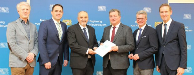 Regierungspräsident Rainer Haselbeck (rechts) hat Staatsminister Christian Bernreiter (3.v.r.) und dem Leiter des Staatlichen Bauamts Passau, Norbert Sterl (3.v.l.), sowie dem Leiter des Bereichs Straßenbau des Staatlichen Bauamts Passau, Kurt Stümpfl (links), im Beisein von Landrat Bernd Sibler (2.v.r.) und dem Bürgermeister der Gemeinde Auerbach, Gerhard Weber, den Planfeststellungsbeschluss für die Ortsumgehung Auerbach überreicht.