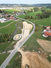 Aus der Luft ist gut zu erkennen, was in den vergangenen beiden Jahren gebaut wurde: Der Grasenseer Bach (links) wurde 2021 verlegt, 2022 folgten der Bau der Unterführung für den späteren Geh- und Radweg, des Regenrückhaltebeckens und der Dammvorschüttungen.