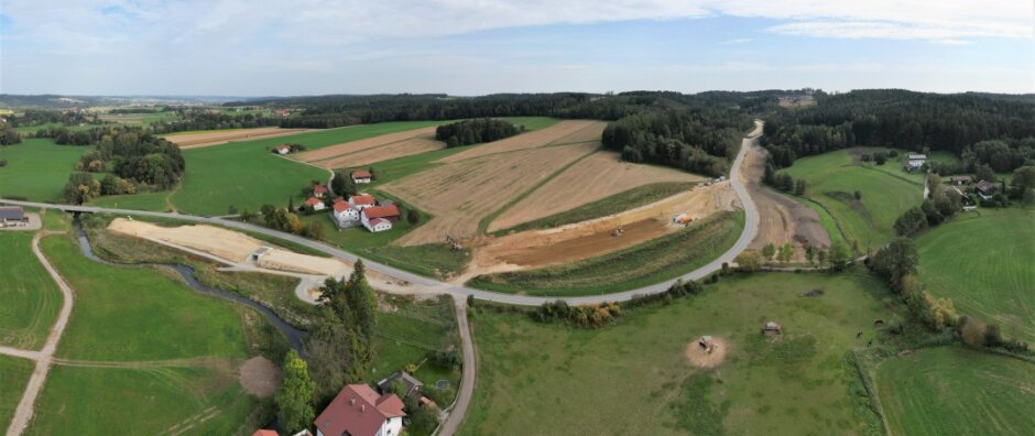 Aus der Luft ist gut zu erkennen, was in den vergangenen beiden Jahren gebaut wurde: Der Grasenseer Bach (links) wurde 2021 verlegt, 2022 folgten der Bau der Unterführung für den späteren Geh- und Radweg, des Regenrückhaltebeckens und der Dammvorschüttungen. - © Staatliches Bauamt Passau